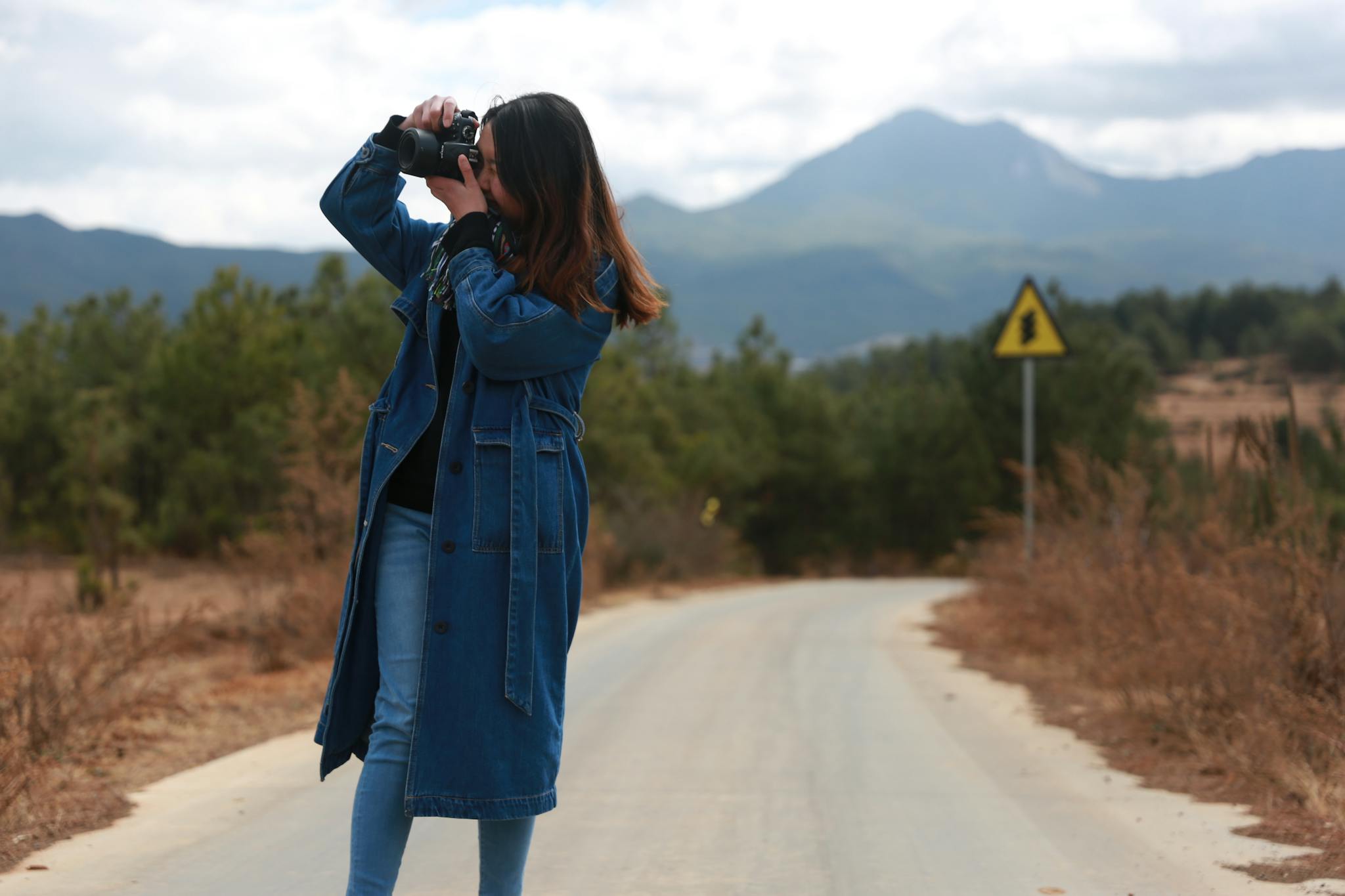 A young woman capturing scenic landscapes in Lijiang, Yunnan Province, China.