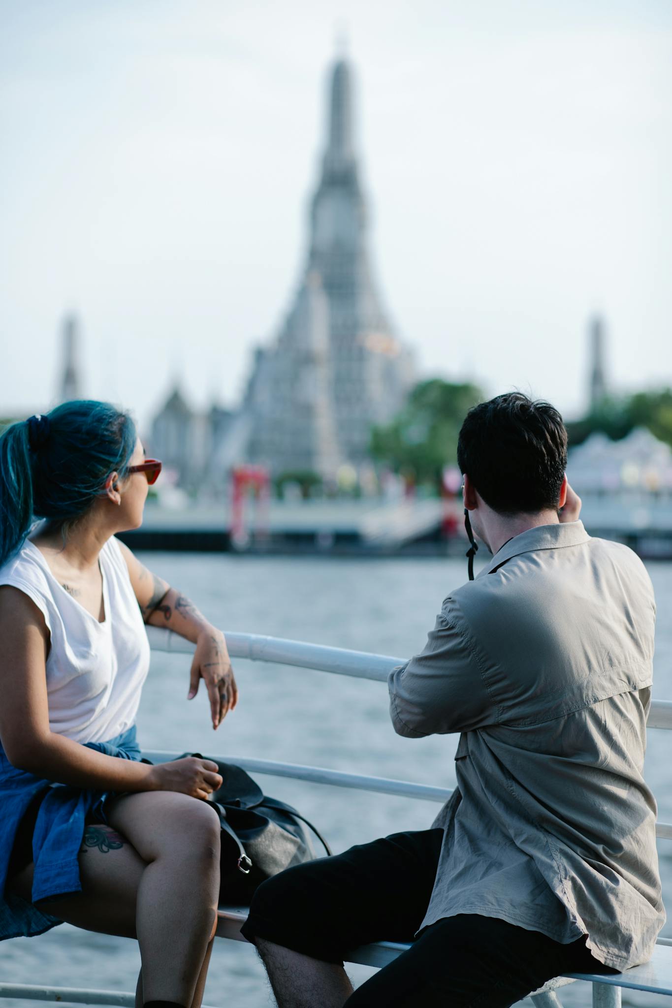 Couple sightseeing Wat Arun from a boat on a sunny day in Bangkok.
