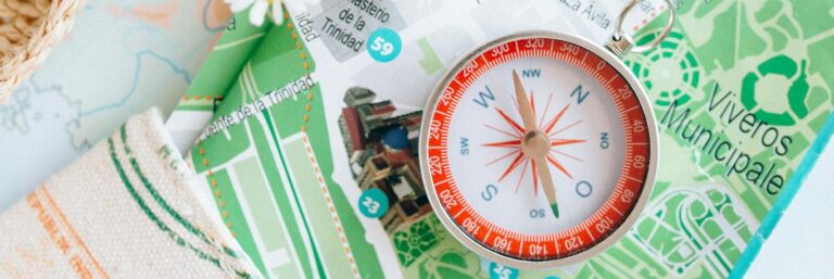 Flat lay of travel items including a map, compass, and flowers, inspiring adventure.