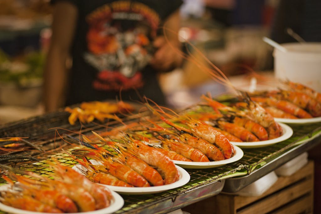 Deliciously grilled shrimps on plates ready to serve at a vibrant Bangkok street food market.