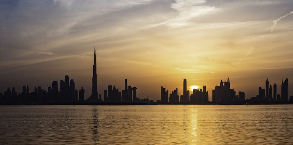 Enchanting view of Dubai's skyscrapers at sunset with the iconic Burj Khalifa outlined against the vivid sky.