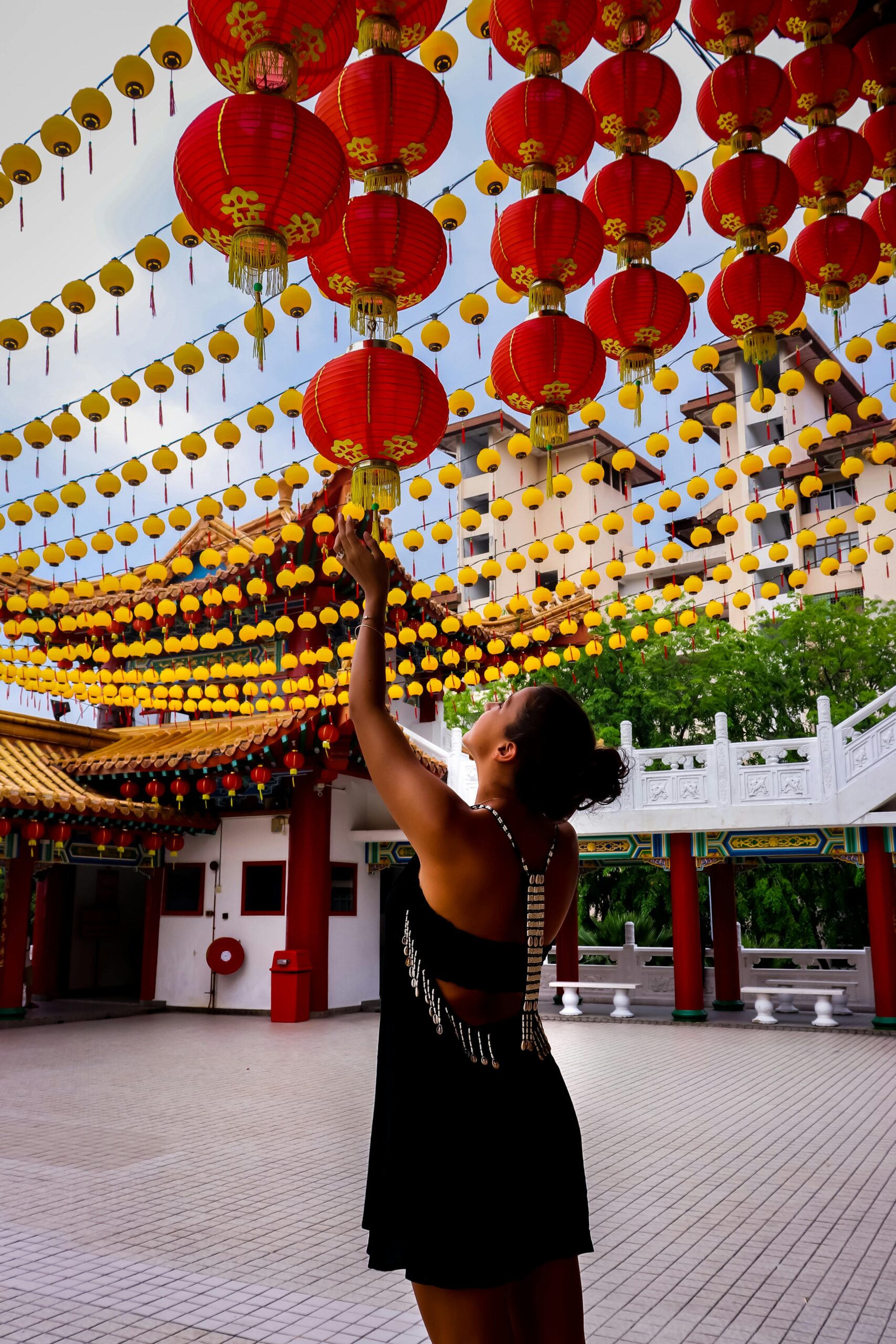 A woman reaches for vibrant paper lanterns at Thean Hou Temple in Kuala Lumpur.