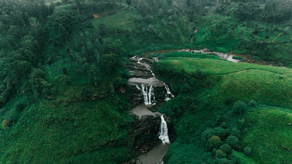 Explore the lush greenery and cascading waterfall in Sri Lanka from an aerial perspective.