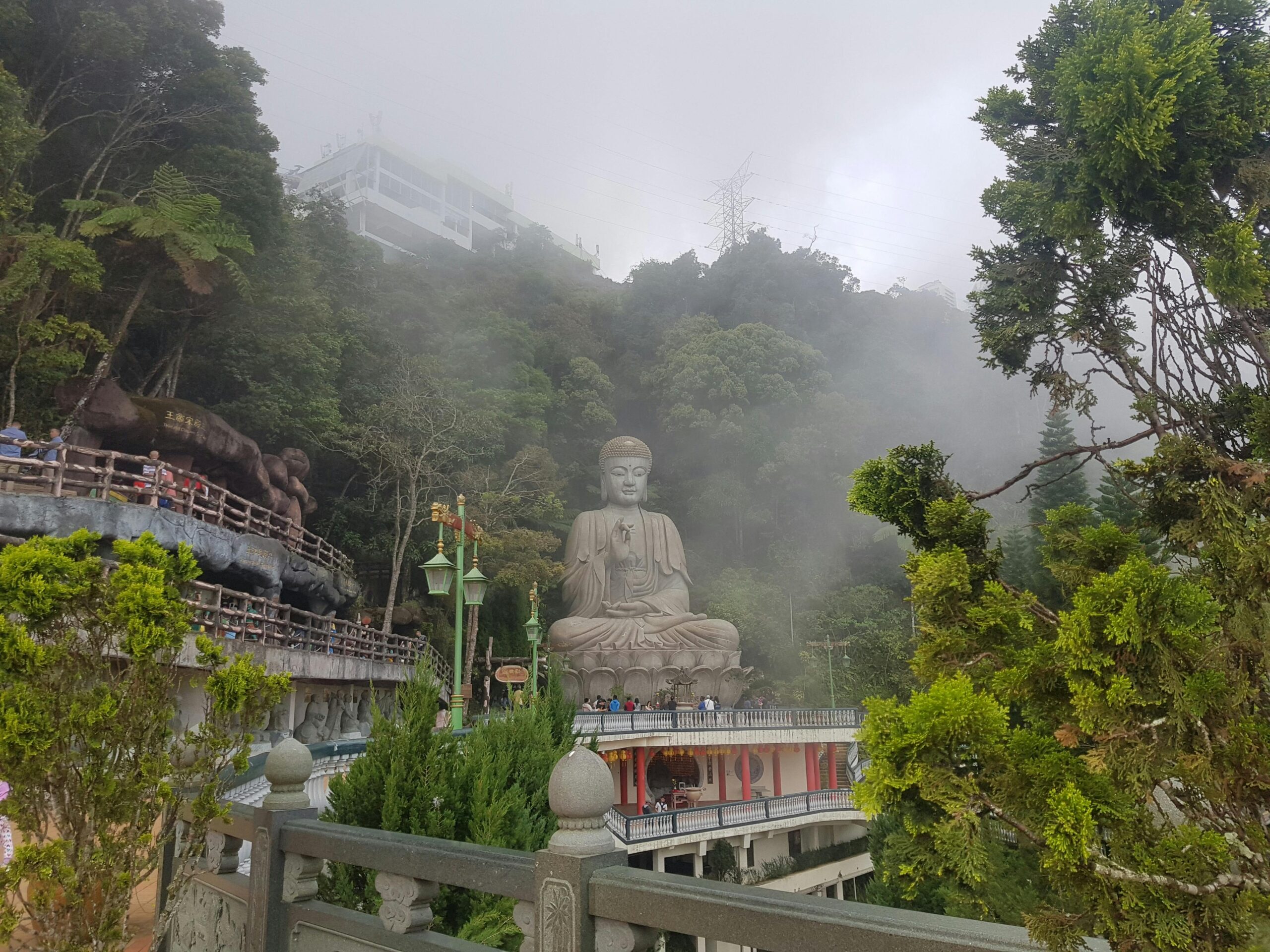 Discover the serene Buddha statue amidst misty lush greenery in Genting Highlands, Malaysia.